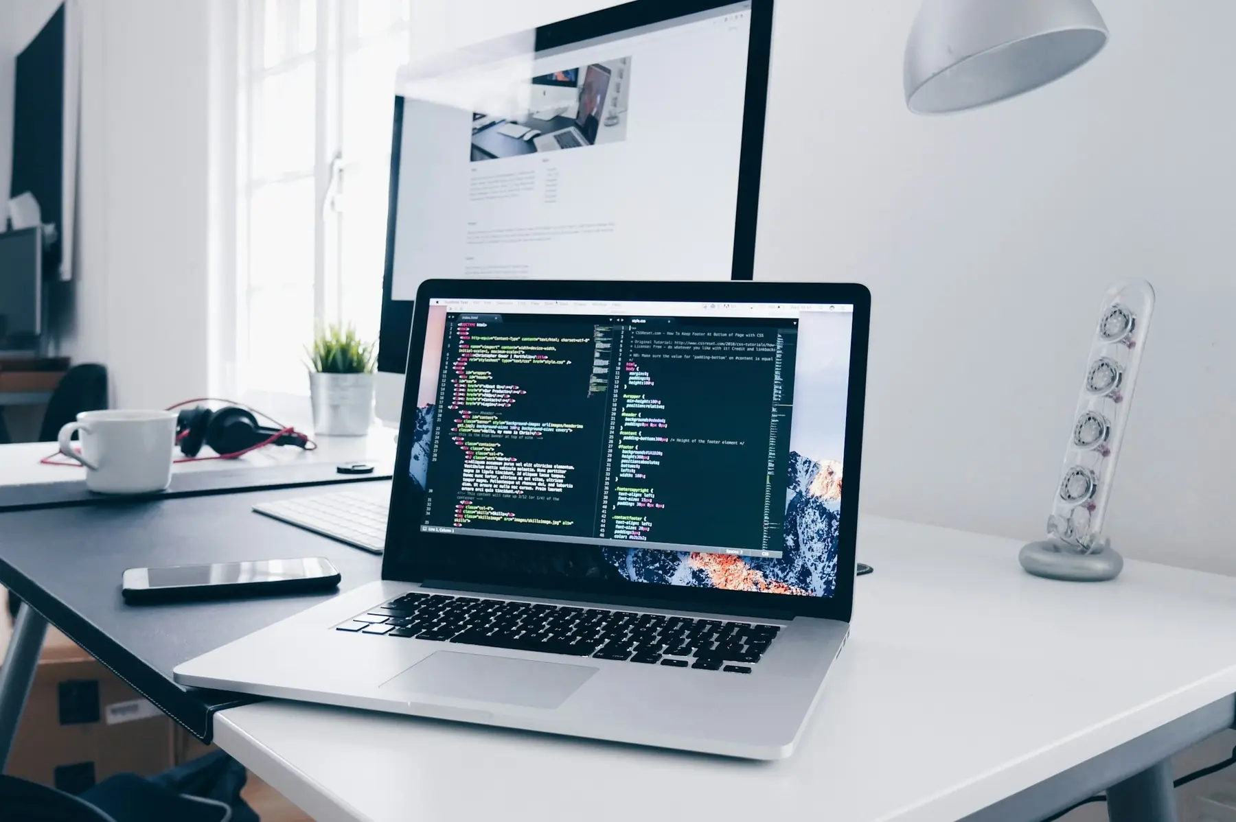 Laptop mit Programmcode auf einem hellen Schreibtisch